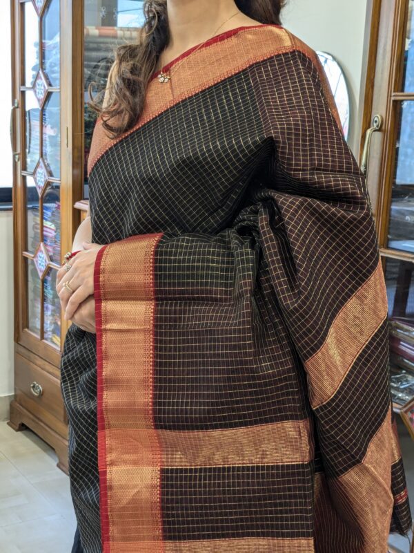 Close-up of black and red Maheshwari saree with zari checks, medium border