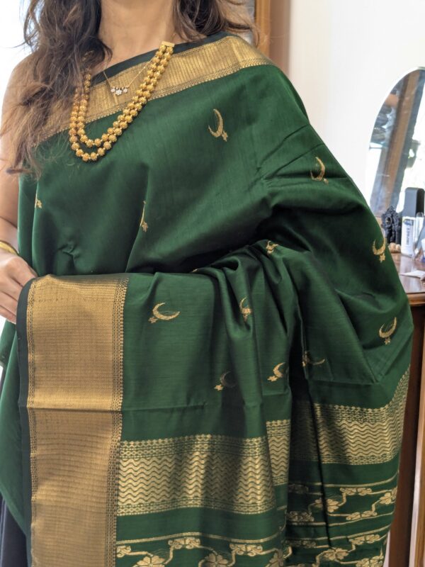 Close-up of bottle green Maheshwari saree with moon and flower motifs, wide-narrow border