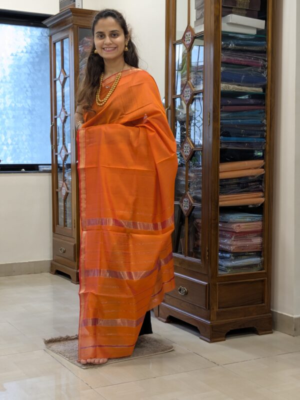Full front view of rust orange handloom Maheshwari saree featuring elegant linear patterns and subtle golden accents.