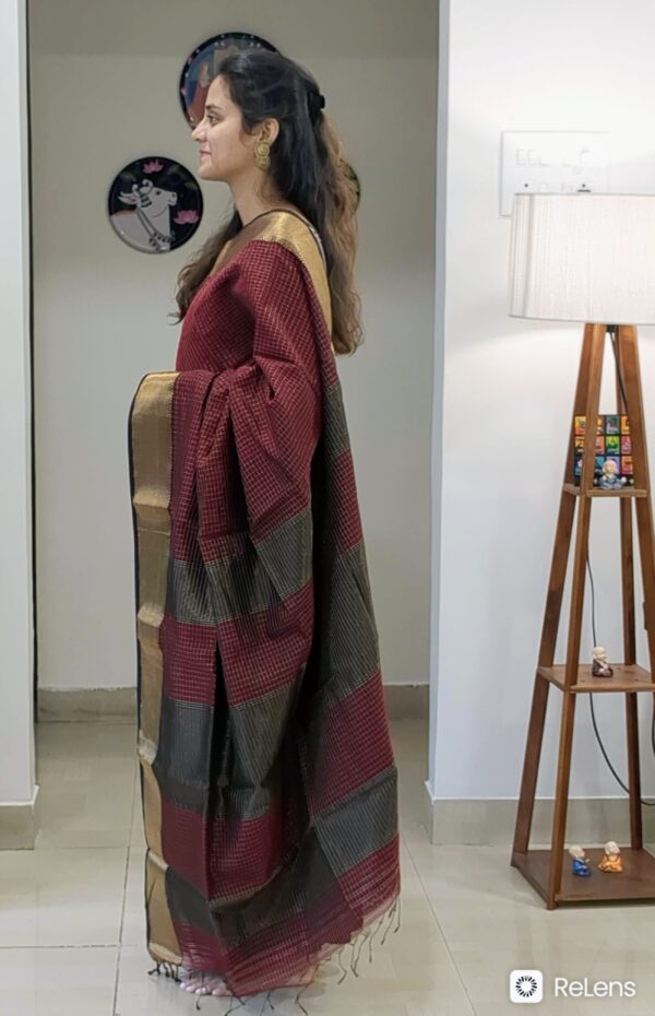 Side view of maroon saree showcasing elegant drape, shimmering texture, and intricate weaving.
