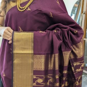 Close-up of plum purple Maheshwari saree with moon and flower motifs, wide-narrow border, and heavy jaali pallu transition.