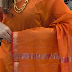Close-up of rust orange Maheshwari silk-cotton saree with striped design, small zari border