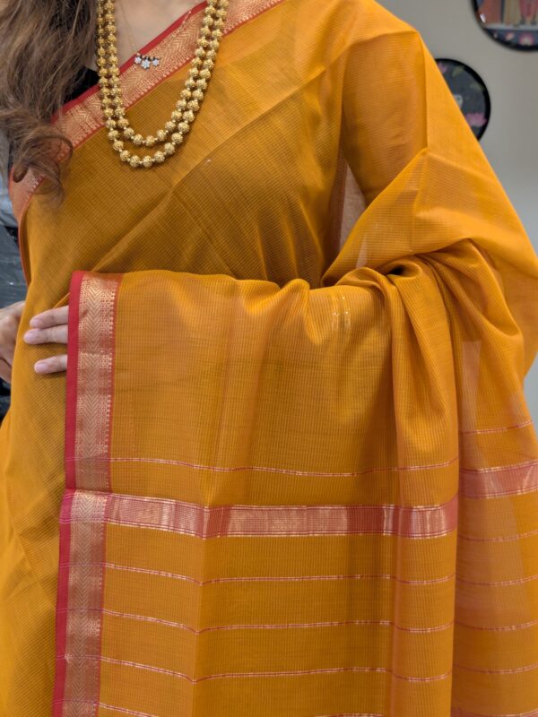 Close-up of rich gold Maheshwari silk-cotton saree with fine lines, small zari border