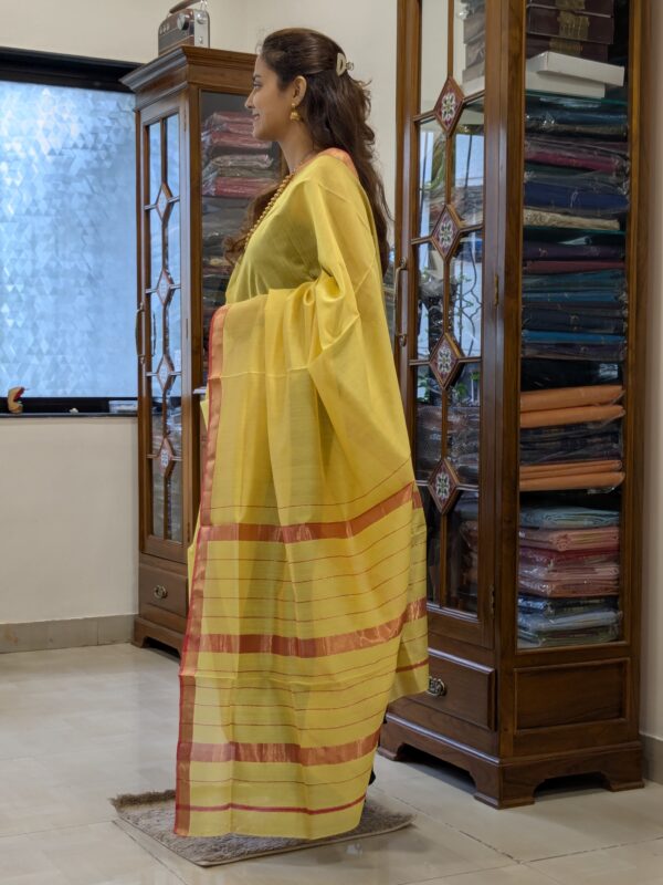 Side view showing soft drape and lightweight texture of the yellow silk-cotton saree.