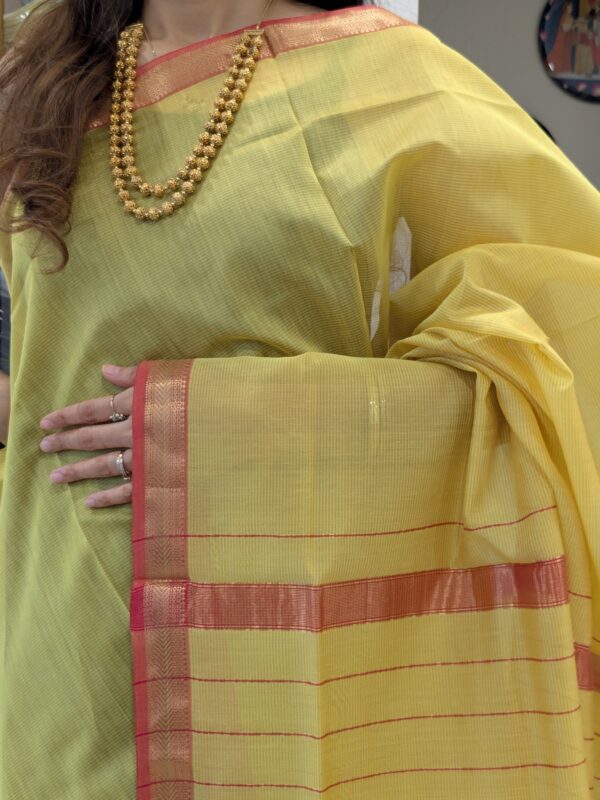 Close-up of yellow Maheshwari silk-cotton saree with line patterns, small zari border