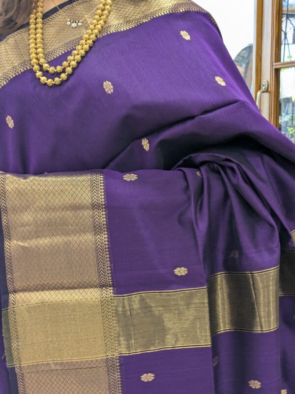 Close-up of purple Maheshwari silk cotton saree with flower butti, wide-narrow border